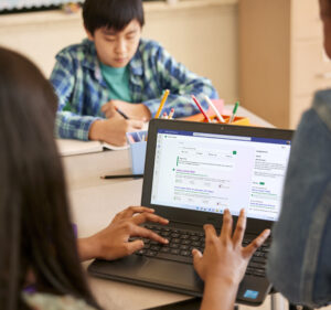 Estudiantes en el aula con una laptop, lápices y cuadernos