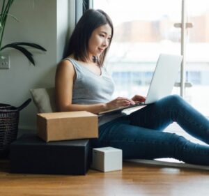 Mujer en casa trabaja en una computadora portátil con paquetes a su lado