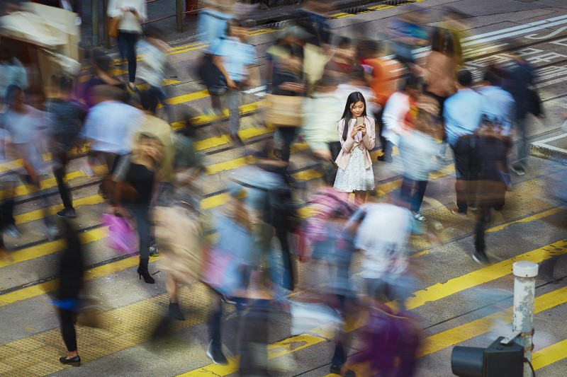 Una mujer mira su teléfono en una calle llena de personas
