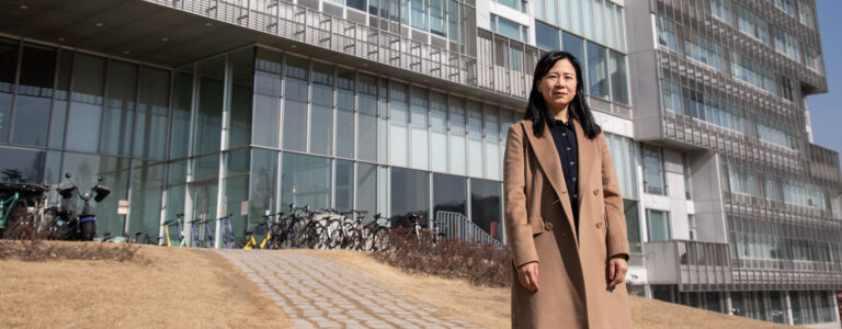 Una mujer de pie frente al edificio de una universidad