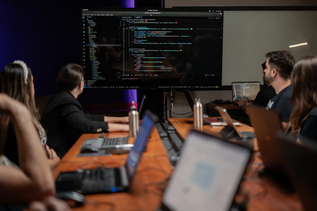 Multiple people sitting at a table with a projector screen in the background