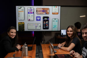 Varias personas sentadas en una mesa con una pantalla de proyector en el fondo