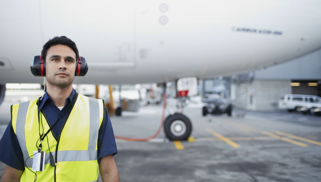 Un operador aéreo frente a un avión en pista