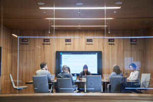 Personas en una sala de juntas trabajan con sus laptops