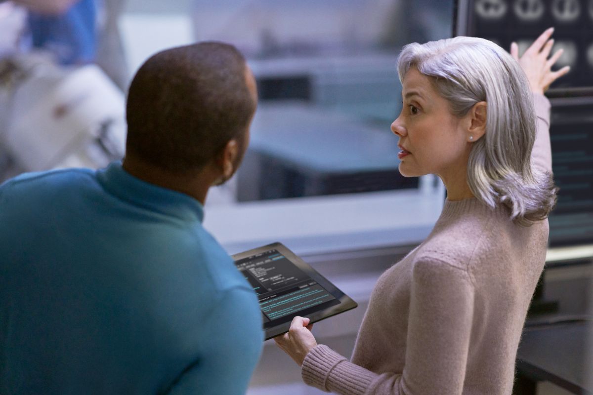 Una mujer sostiene una tablet mientras un hombre la observa