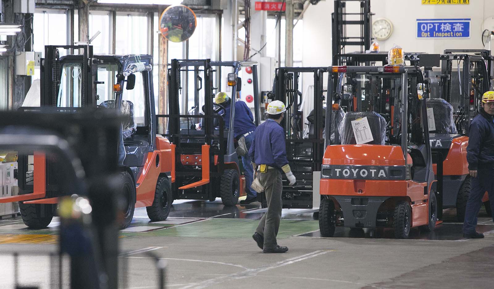Workers in a plant shown with loading vehicles.