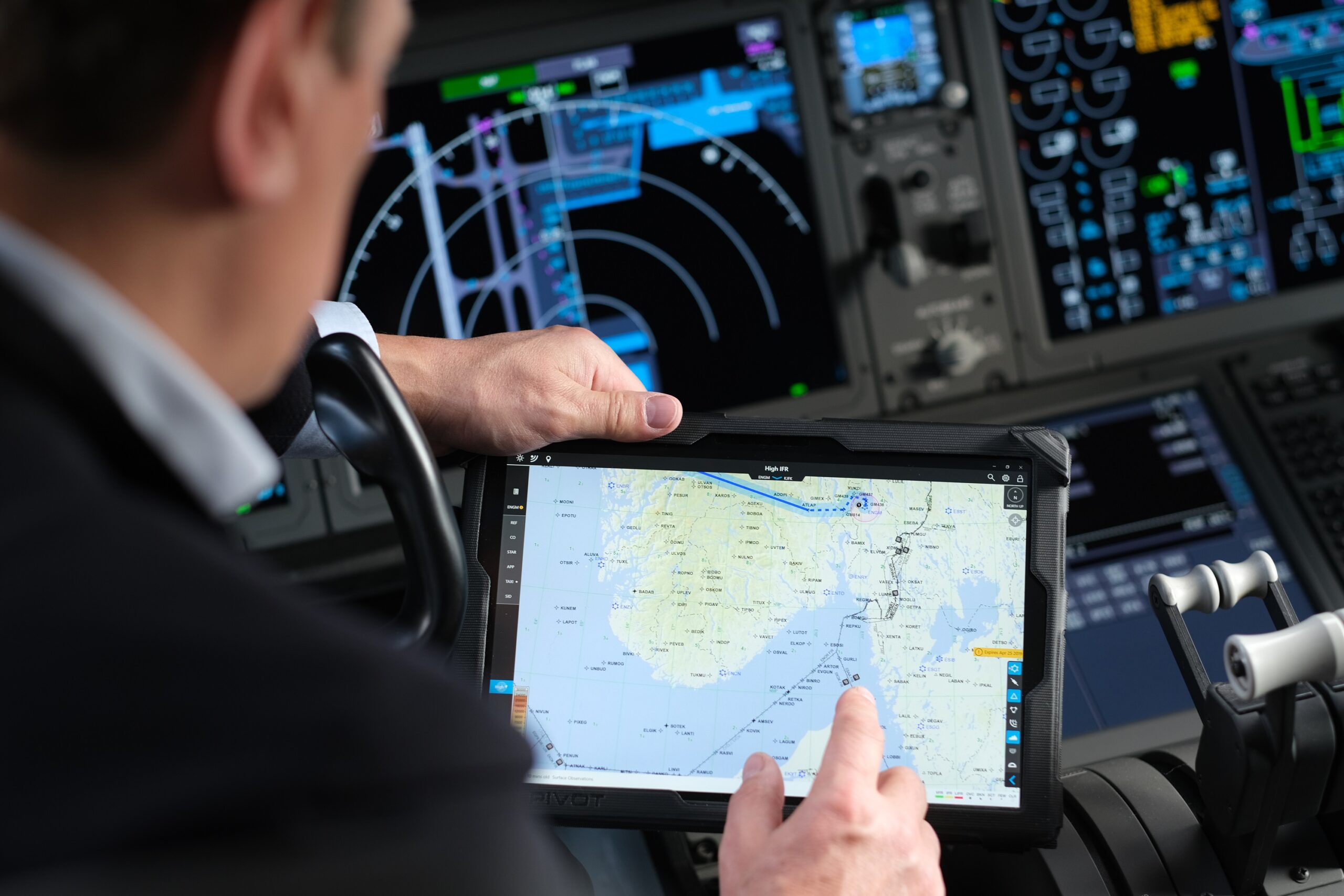 An airline pilot sitting in the cockpit looks at a Surface screen that is displaying a map.