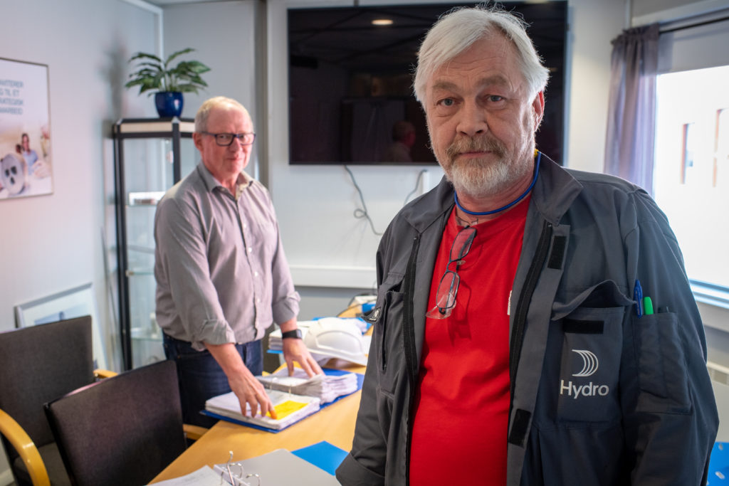 Two Norsk Hydro executives are shown standing in an office, looking concerned.