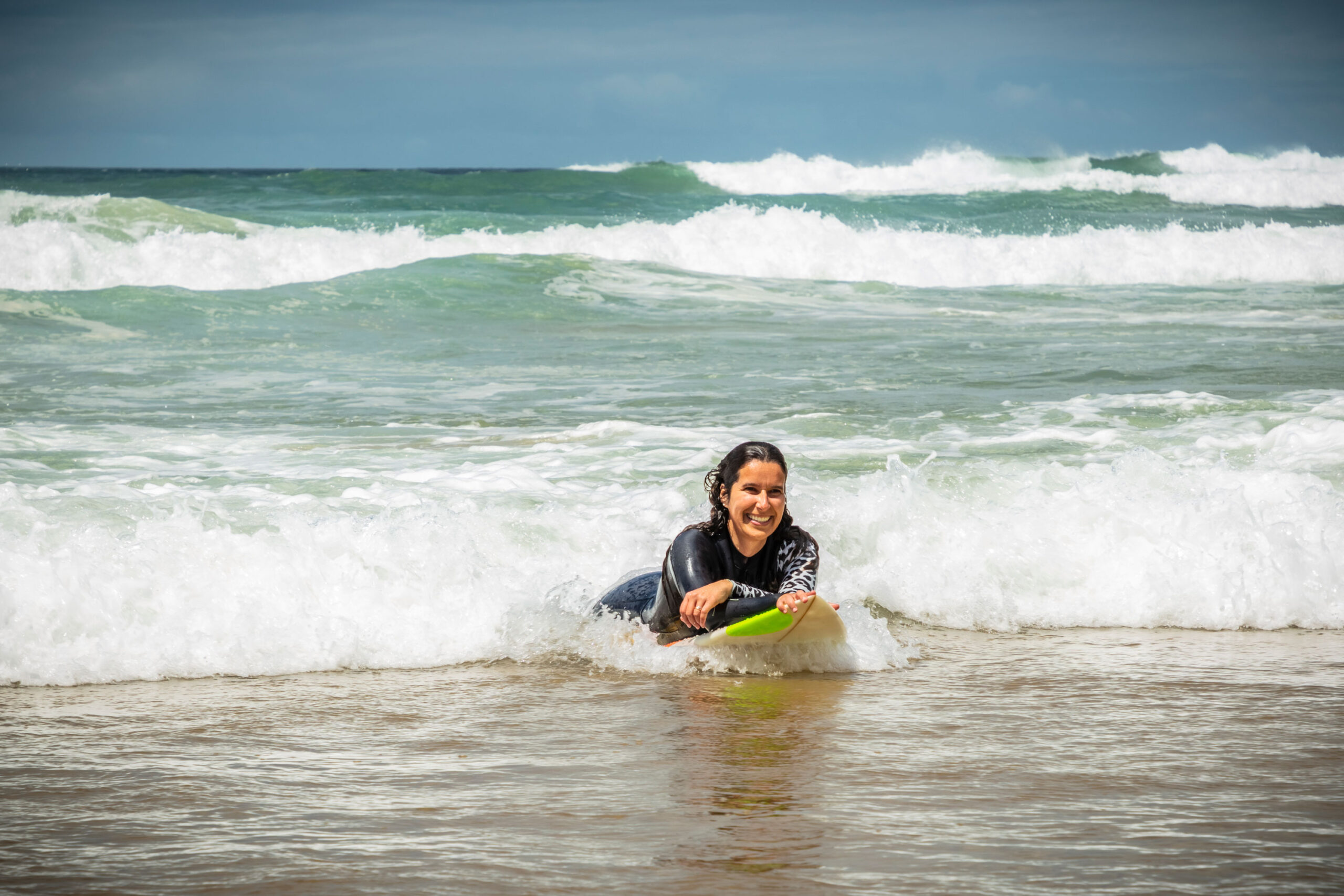 Woman lays on surf board in ocean