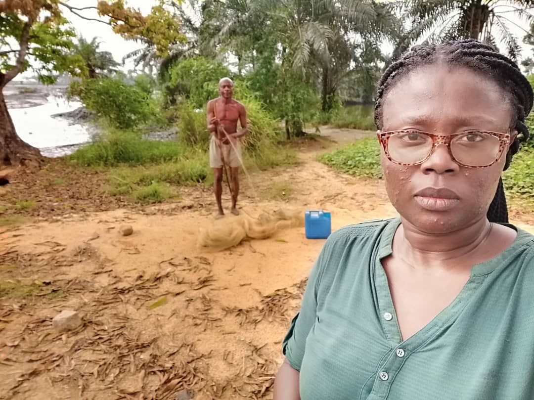 Woman stands near contaminated waterway in Ogoniland, Nigeria.