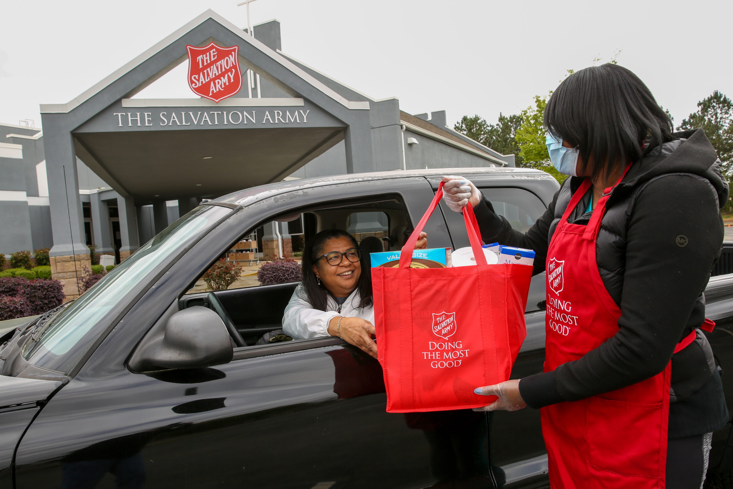 A Salvation Army workers hands a bag of food to a woman in a car in Georgia.