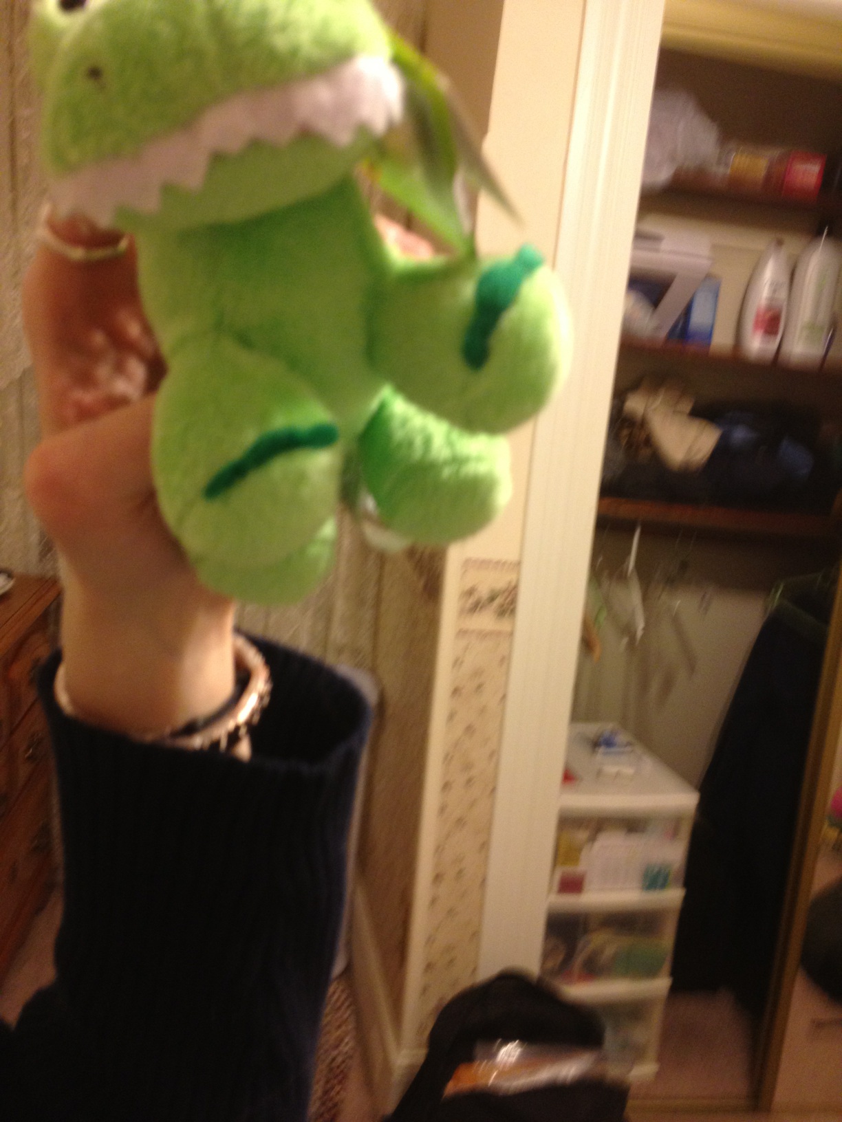 A person holding a plush toy of a cartoon dinosaur in their hand.