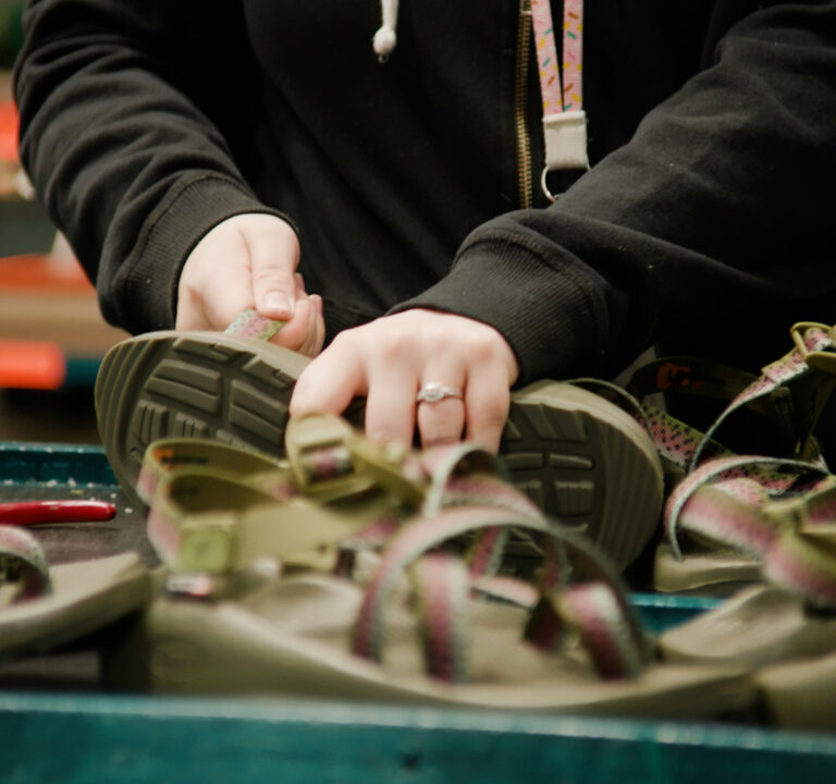 A worker's hands tinker with shoes.