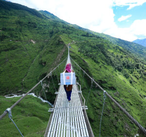 A health care worker in Nepal walks across a bridge