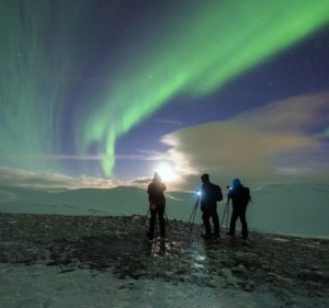 Silhouettes of three people against the Northern Lights