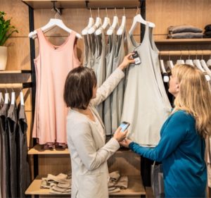 Two women using a mobile device to look up information about a top in a retail store
