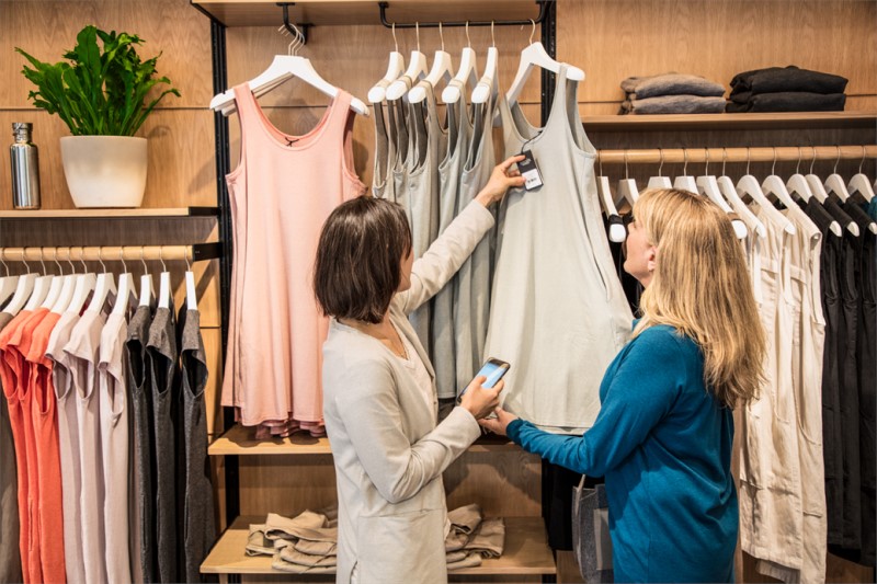 Two women using a mobile device to look up information about a top in a retail store
