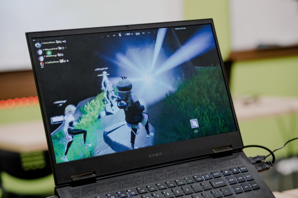 A laptop screen displays a scene from a Fortnite game. 