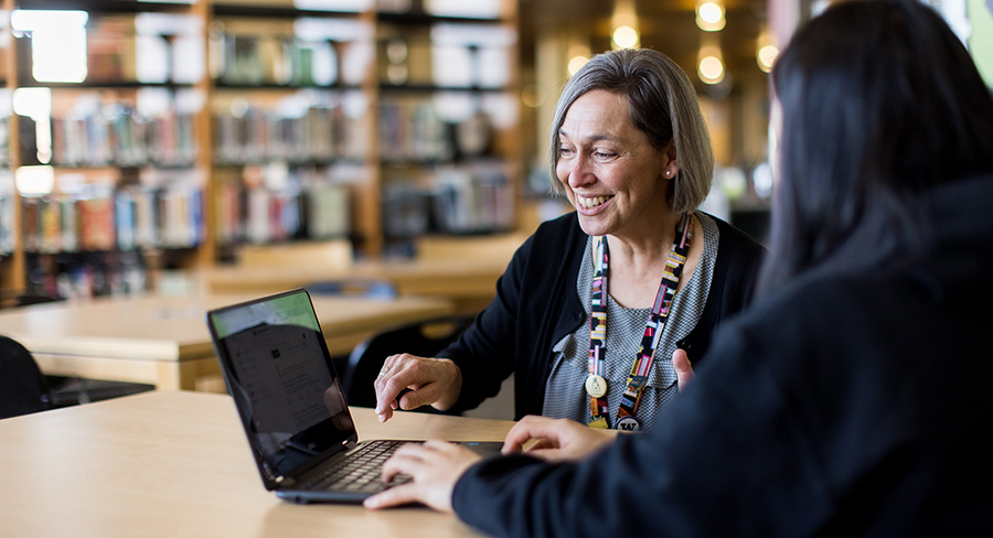 Woman smiles and points at laptop