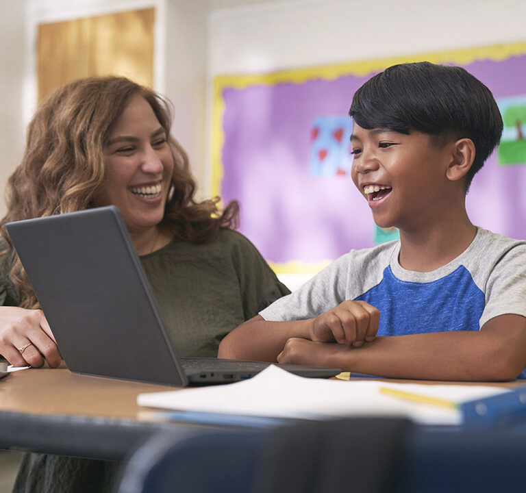 Teacher and student enjoy a laugh together in front of a laptop computer