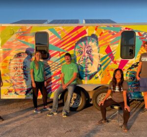 A group of employees from Schneider Electric and Footprint Project stand in front of a solar-powered trailer.
