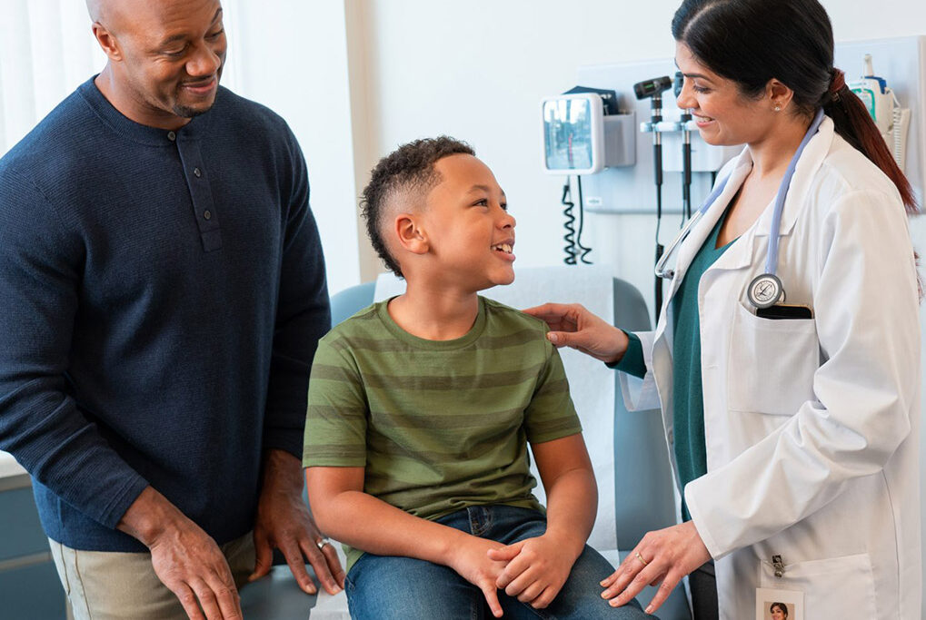Doctor seeing young patient with his father standing by