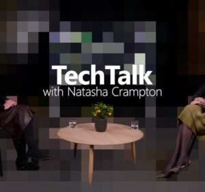 Two people sit in chairs with a table in the center, "TechTalk with Natasha Crampton" over a pixelated center