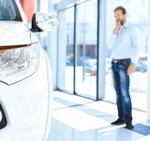 Man pondering whether to purchase a car on a showroom floor