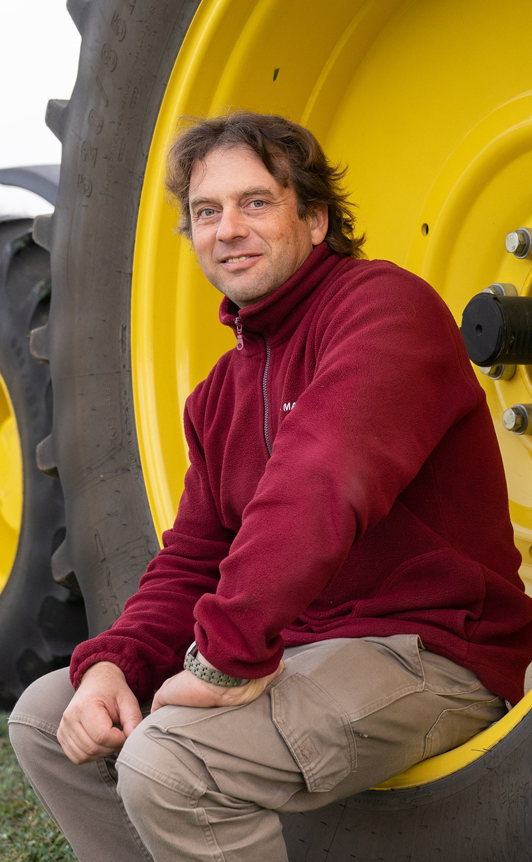 A man sits on the side of a tractor wheel