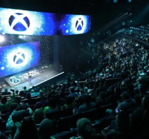 Audience members viewing a stage where multiple Xbox logos are displayed