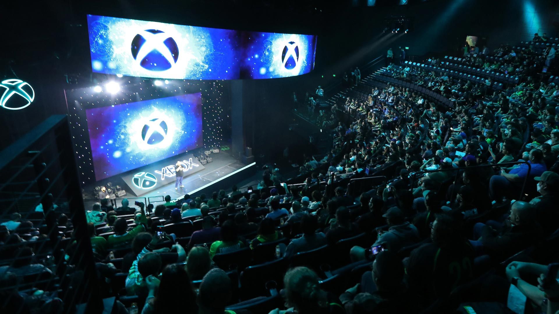 Audience members viewing a stage where multiple Xbox logos are displayed