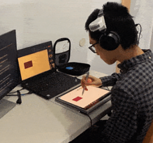 Man wearing headphones and using a digital pen to interact with a tablet device