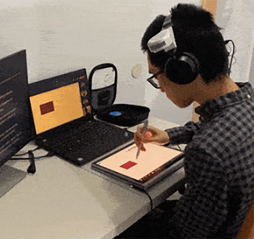 Man wearing headphones and using a digital pen to interact with a tablet device