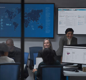 Five people working in a security operations room with a map of the world behind them