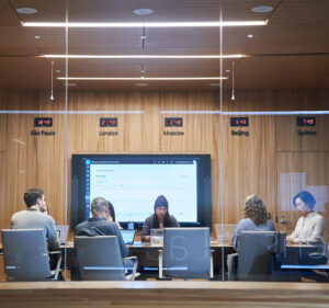 Six people working in a conference room with a large display screen behind them