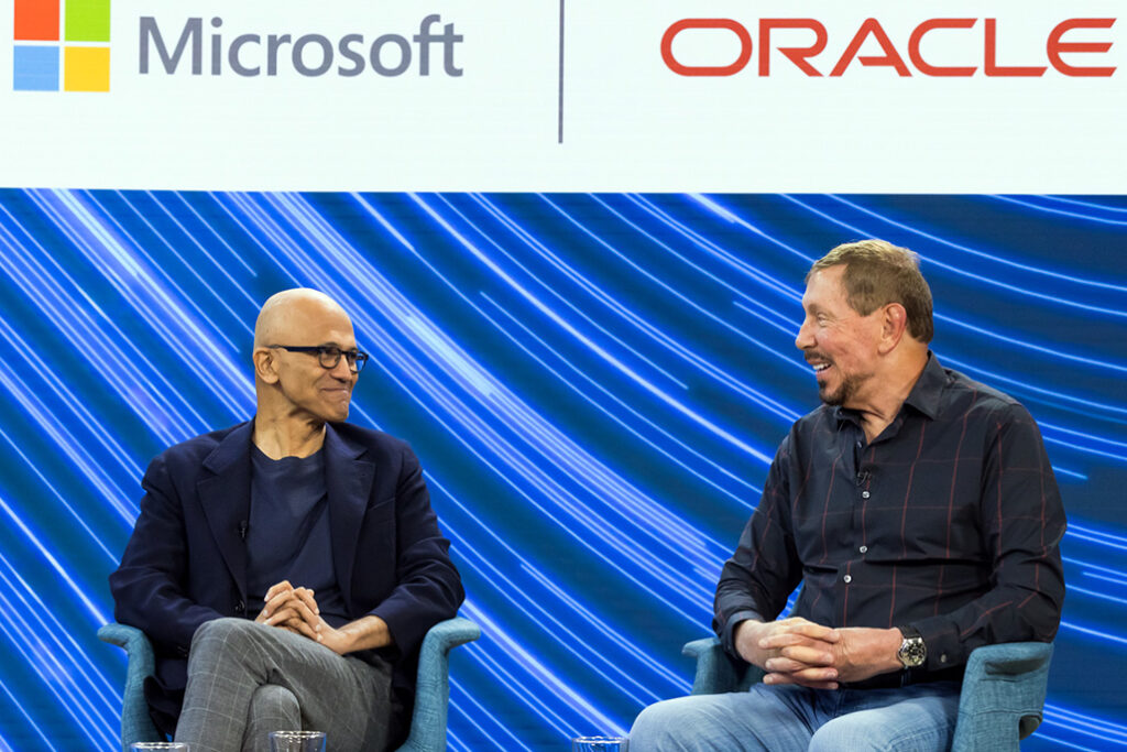 Satya Nadella and Larry Ellison seated on stage, with the logos of Microsoft and Oracle behind them