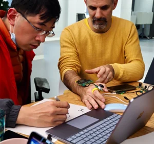 Two men working together on a device worn on the wrist