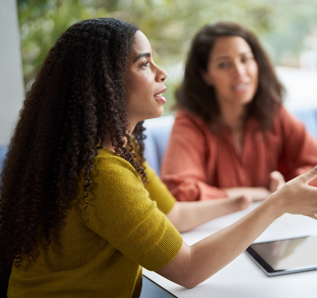 Woman talking at an office meeting while another woman looks on