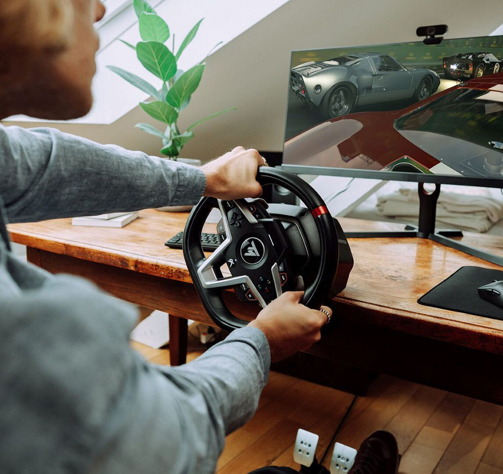 Man playing Forza Motorsport game using a steering wheel accessory