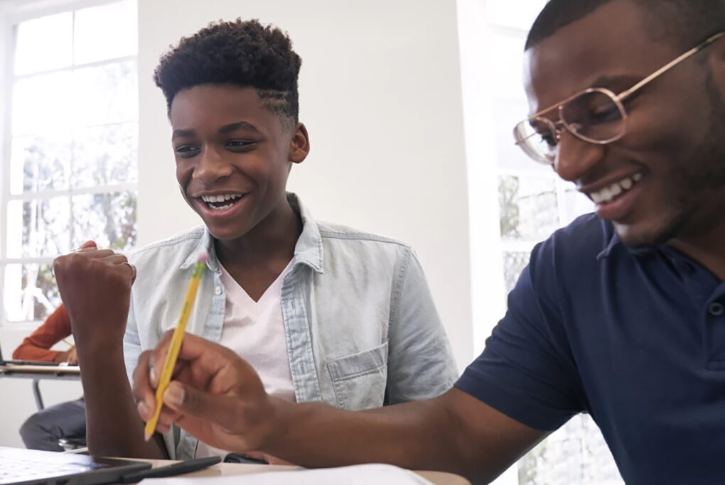 Two young men smiling as they work together on a classroom project