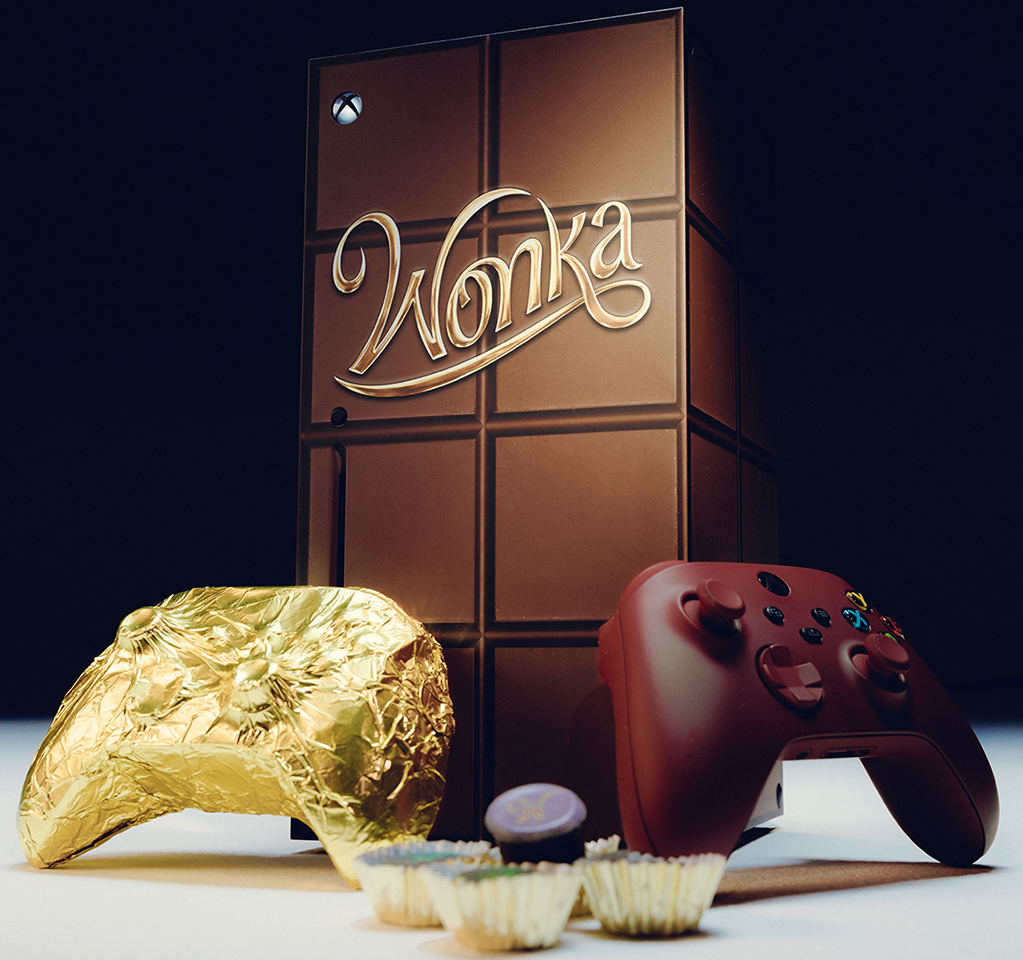 Wonka-themed Xbox console along with two Wonka-themed Xbox controllers, one wrapped in gold foil