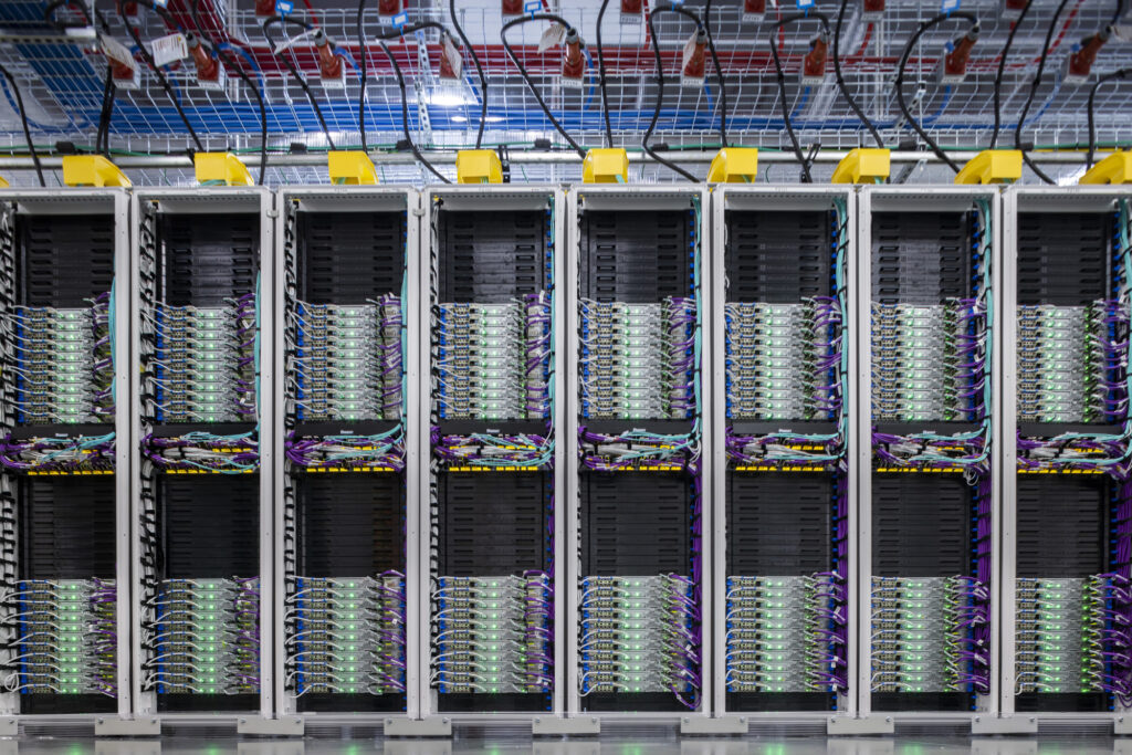 Wide shot of rows of data center servers connected by colorful wires.
