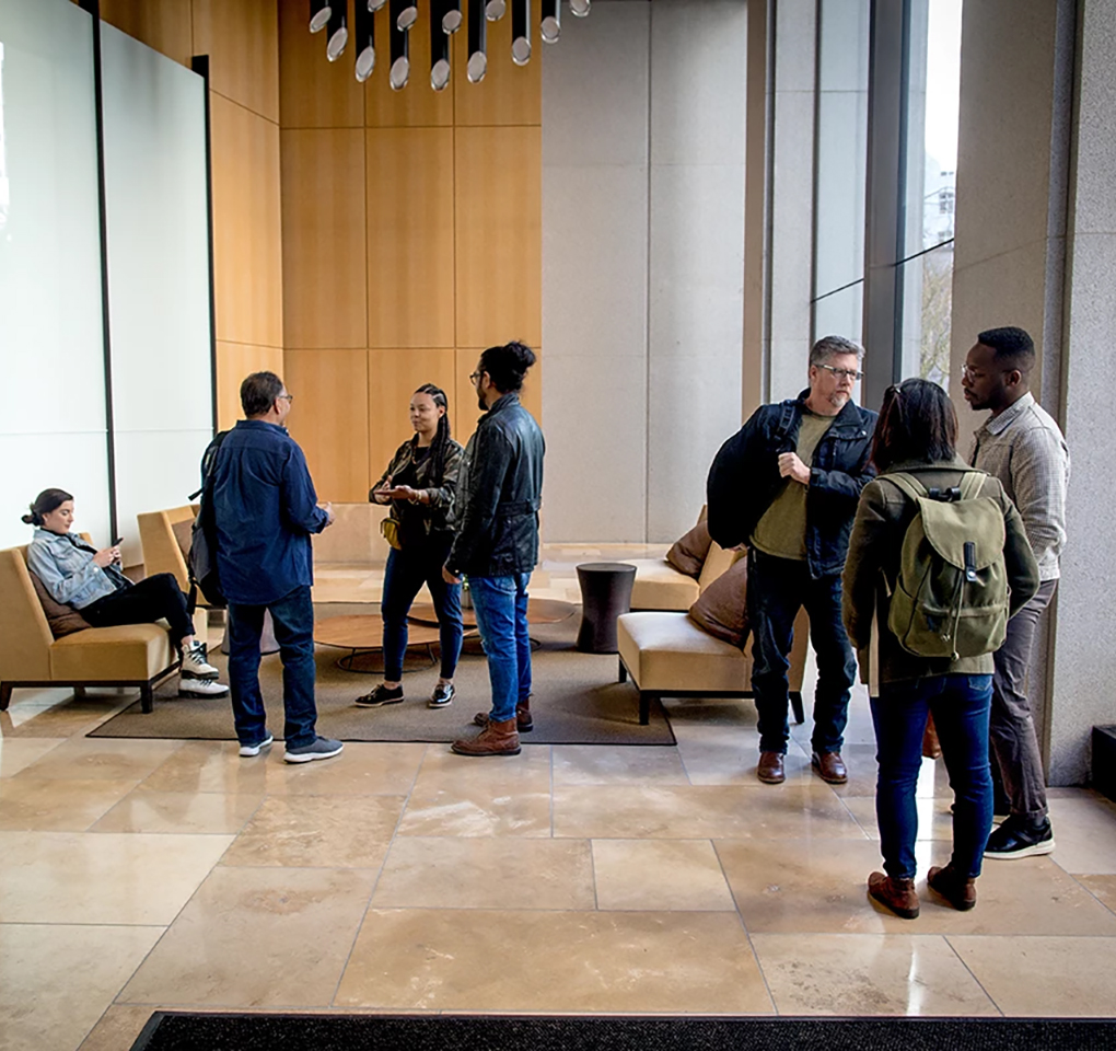 Seven young adults chatting in a building lobby