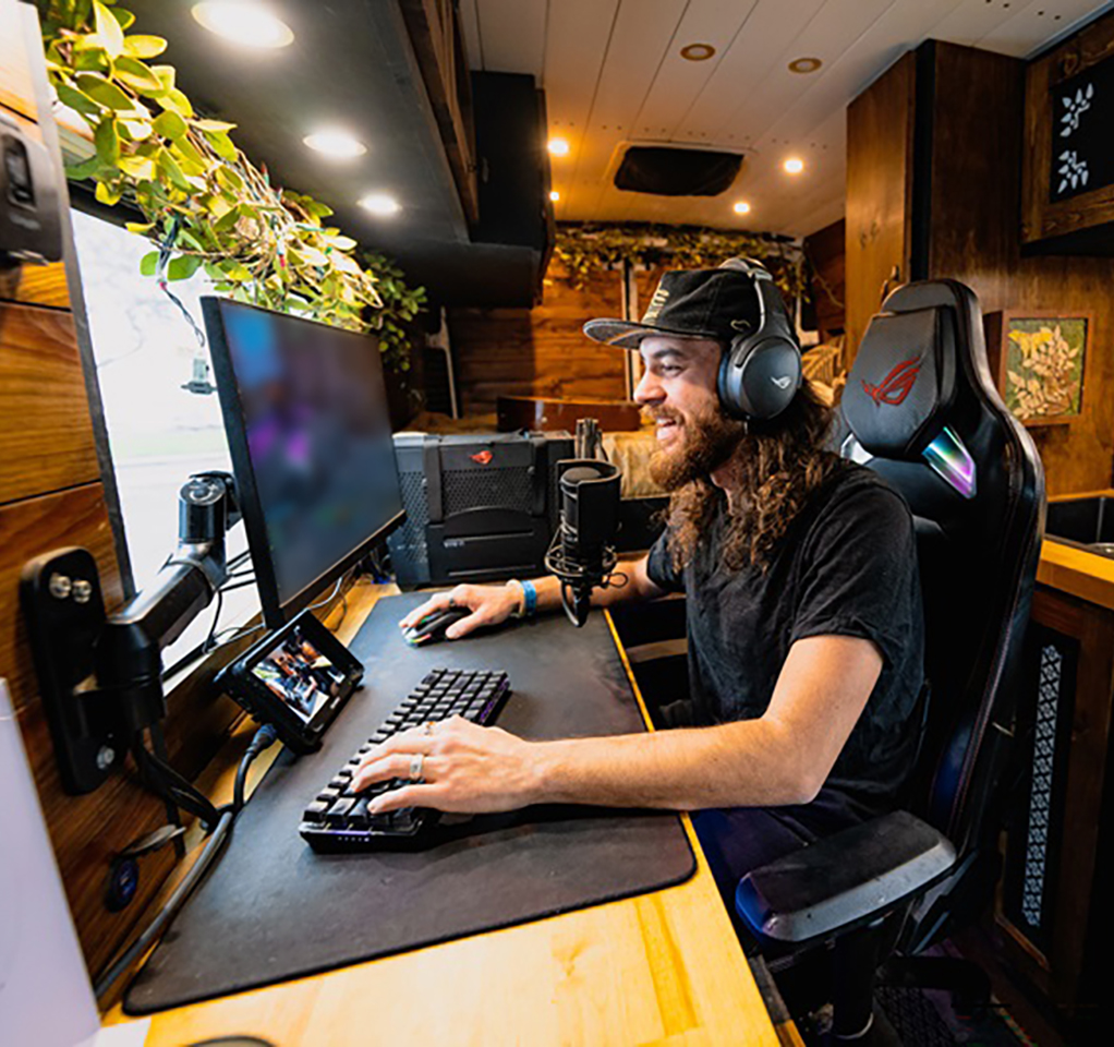 Man in van playing video games on desk