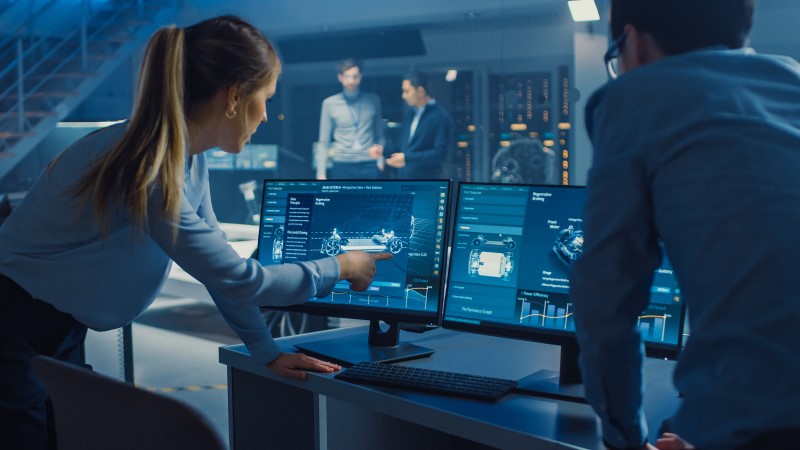 Woman points to screen of desktop computer in an operations center
