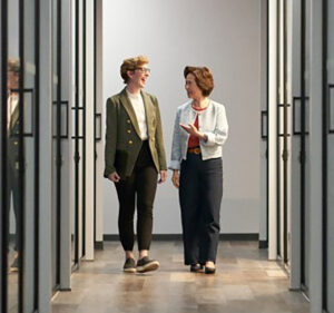 Two women walking between rows of severs in a datacenter