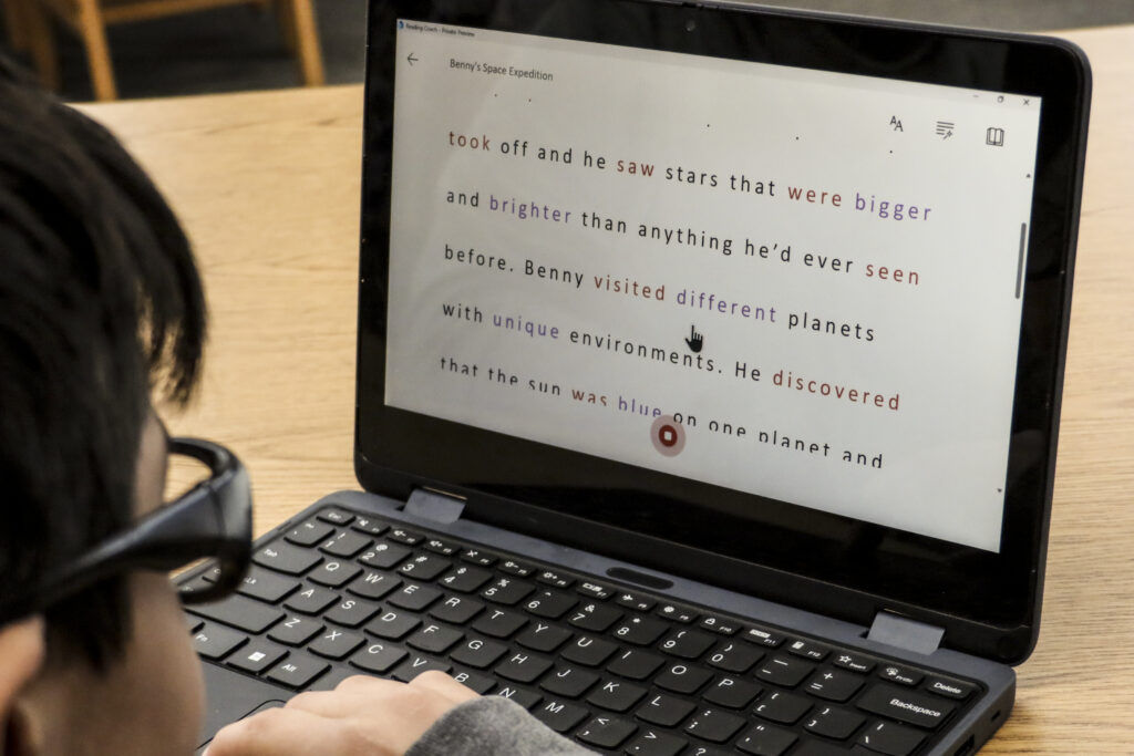A boy reads a computer screen showing a story that was freshly generated by Reading Coach.