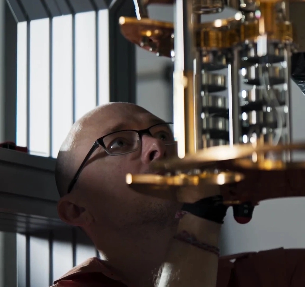 Man looking up at and working on quantum computing hardware