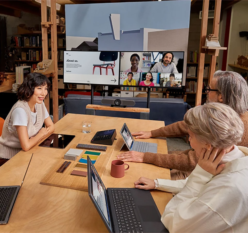 Three people in an office conference room meeting with others over Microsoft Teams