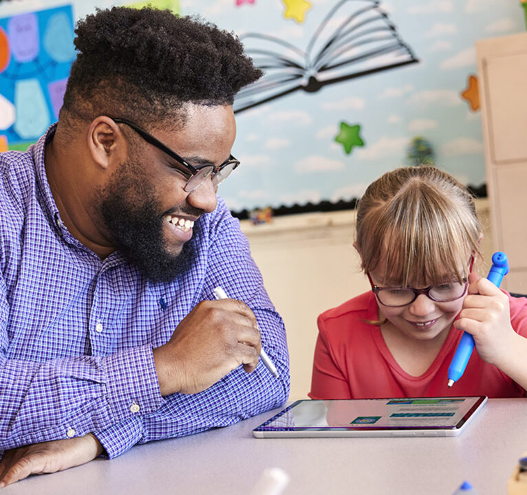 Teacher using a tablet device to help a student in a classroom